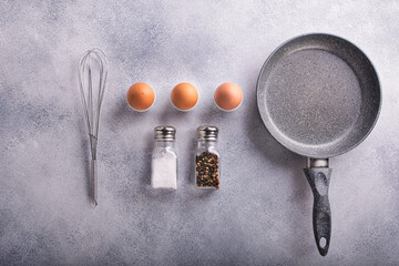 ingredients and dishes for making scrambled eggs are laid out on a light stone background
