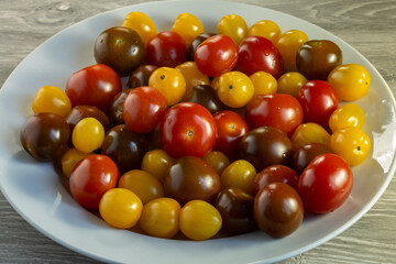 Multicolored tomatoes of different varieties in a dish. Fashionable vegan food.