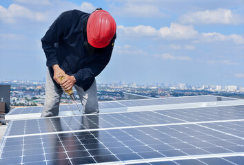 The technician is drilling holes to mount the solar panel Cell with electric drill on top of the roof.