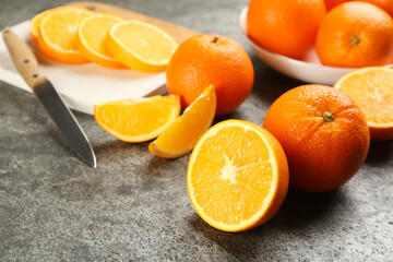 Whole and cut delicious ripe oranges on grey table