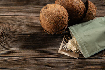 coconut flakes in a coconut shell on an old wooden background, top view close up