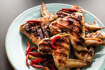 grilled chicken wings laid out on a plate in a bunch, sprinkled with chili
