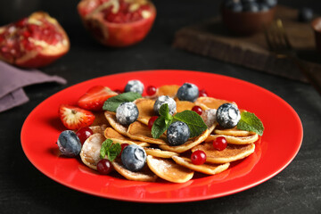 Cereal pancakes with berries and mint on black table