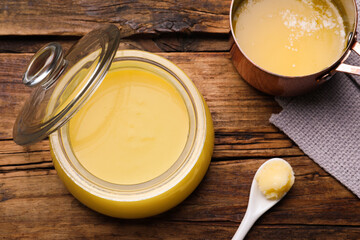 Ghee butter in dishware on wooden table, flat lay