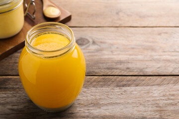 Glass jar of Ghee butter on wooden table. Space for text
