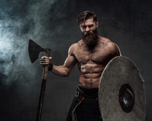 Furious viking with shield and axe in dark background