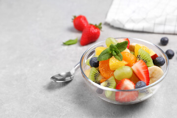 Delicious fresh fruit salad in bowl on light table, space for text