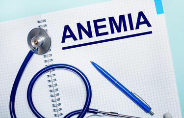 On a light blue background, an open notebook with the word ANEMIA, a blue pen and a stethoscope....
