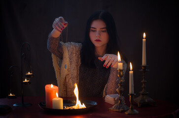 young witch  with fire and  burning candles on  dark background