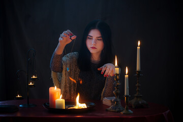 young witch  with fire and  burning candles on  dark background