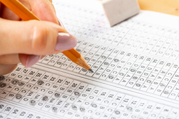 Obraz premium The student fills in the answers to the test in the exercise and examination paper with a pencil. education concept.