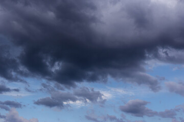 Naklejka na ściany i meble Thunderstorm clouds texture. Storm sky with dark rainy cumulus clouds against blue sky background 