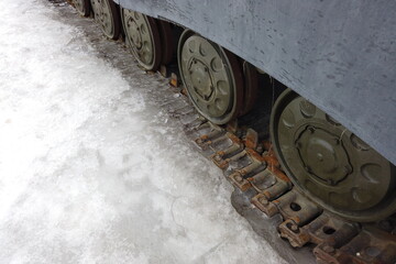Fototapeta na wymiar The caterpillar of an old tank frozen in the ice