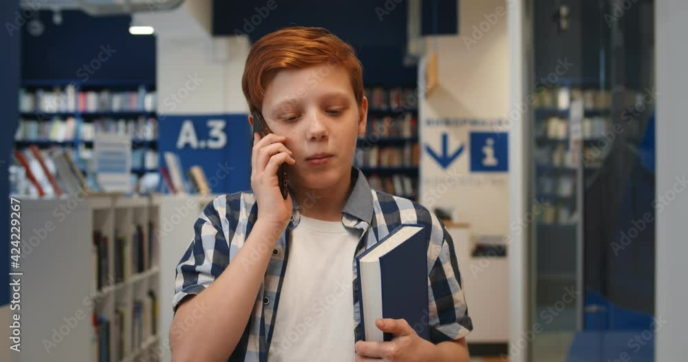 Canvas Prints teen schoolboy walking in school library and talking on smartphone