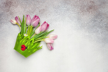 Easter concept. Tulips bouquet in the bag  on a gray background. Top view. Copy space