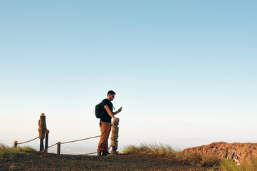 Latin man using smart phone after a hiking trail in the mountains