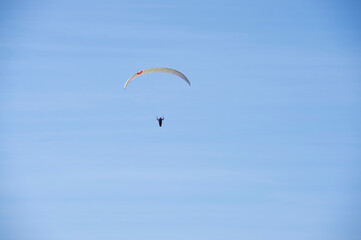 Im blauen Himmel ist ein Gleitschirmflieger unterwegs