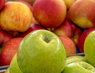 a green apple on red apples background, fresh vegetarian food