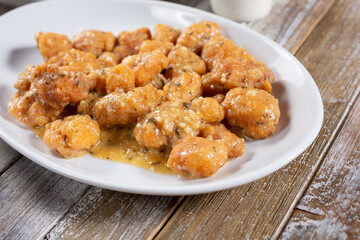 A view of a plate of boneless chicken wings in garlic sauce.
