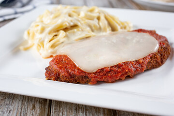 A view of a plate of chicken parmigiana and fettuccine Alfredo.