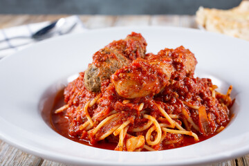 A view of a plate of spaghetti, featuring meatballs and sausages.