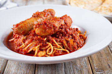 A view of a plate of spaghetti and sausage.
