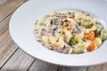 A view of a plate of colorful tortellini in cream sauce.