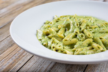 A view of a plate of pesto penne pasta.