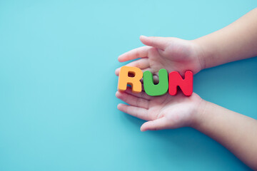 Run word on children kid hands on blue background.Endurance, exercise, kid child play, sport, escape, Action motion, fitness, cardio, sport wear business, Vitality,Run word sport presentation slide.
