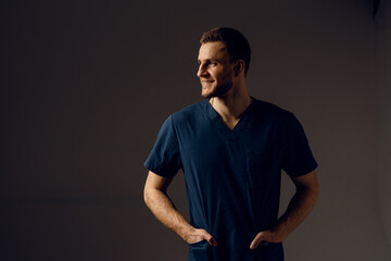 Surgeon weared in medical robe on dark background. Handsome doctor posing in studio