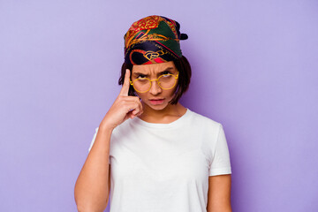 Young mixed race woman wearing a bandana isolated on purple background pointing temple with finger, thinking, focused on a task.