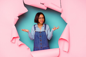 Young mixed race woman behind a broken background upset screaming with tense hands.