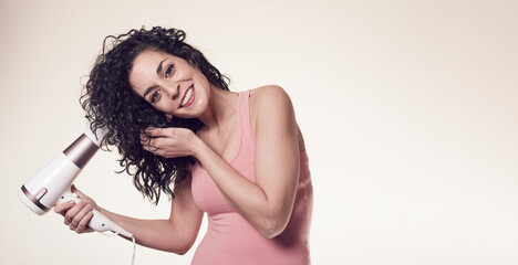 young black curly haired woman follows the curly girl method with suitable curly hair care products using a blow dryer to get curls and waves in her hair. care and beauty concept. copy space