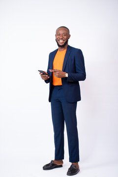 handsome young black man wearing a suit using his phone and credit card, standing on a white background