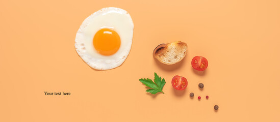 Fried egg with toast, tomato, spice and parsley on a pastel peach background. Banner. Creative layout. Top view, flat lay.