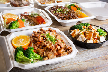 A view of several varieties of teriyaki entrees on a wood table surface.