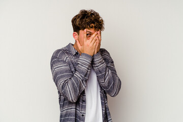 Young caucasian man isolated on white background blink through fingers frightened and nervous.