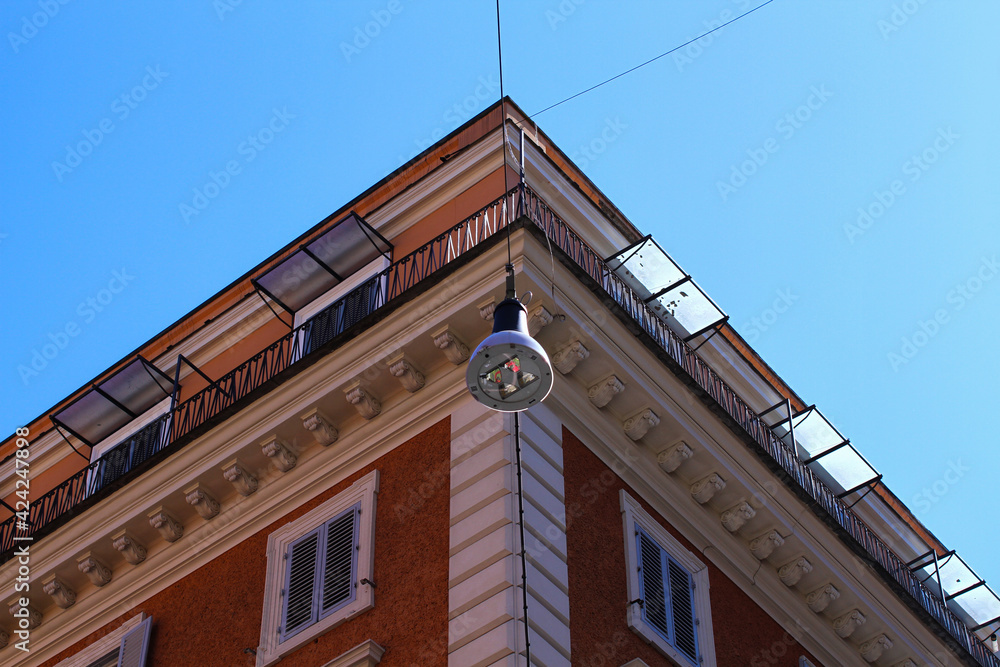 Wall mural light orange and cream colored residential building in rome, street lamp, blue sky.