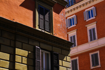 Obraz premium Light orange and red colored residential building in Rome, blue sky.