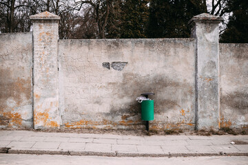 street trash can in front of an old limestone wall
