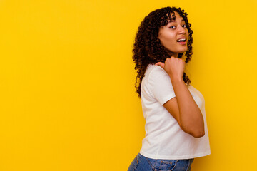 Young mixed race woman isolated on yellow background points with thumb finger away, laughing and carefree.