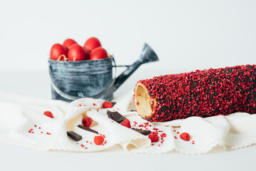 Traditional Hungarian kurtos kalacs with raspberry flavor known as chimney cake on a rustic tablecloth and red Easter eggs. 