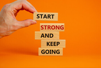 Start strong and keep going symbol. Concept words 'Start strong and keep going' on wooden blocks on a beautiful orange background. Businessman hand. Business, motivational and start strong concept.