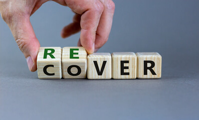 Recover symbol. Concept word 'recover' on wooden cubes on a beautiful grey table. Businessman hand. Grey background. Business and recover concept. Copy space.