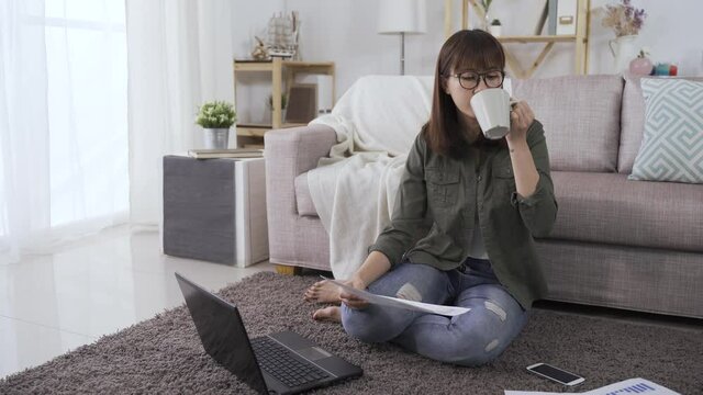 full length woman accountant sipping morning coffee and preparing financial statement with document and personal computer during lockdown.