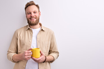 Handsome Caucasian Man In Casual Wear Posing At Camera Holding Yellow Mug In Hands