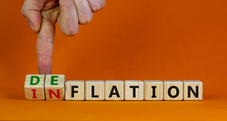 Inflation or deflation symbol. Businessman turns cubes and changes the word inflation to deflation. Beautiful orange background, copy space. Business, inflation or deflation concept.