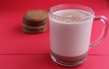 Cocoa hot chocolate in a glass mug on a red background with room for text copyspace and liver on hellish plan