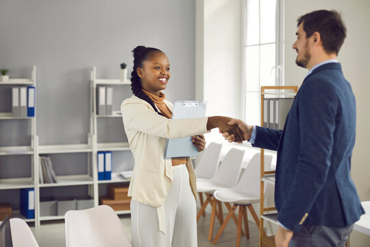 Friendly African american female bank manager shakes hands welcoming a client who has come for legal advice. Man came to the bank office to get advice on his finances, loans, mortgages or insurance.