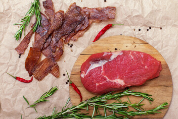 Jerky meat and raw beef on brown craft paper background. Ingredients for cooking meat snacks....
